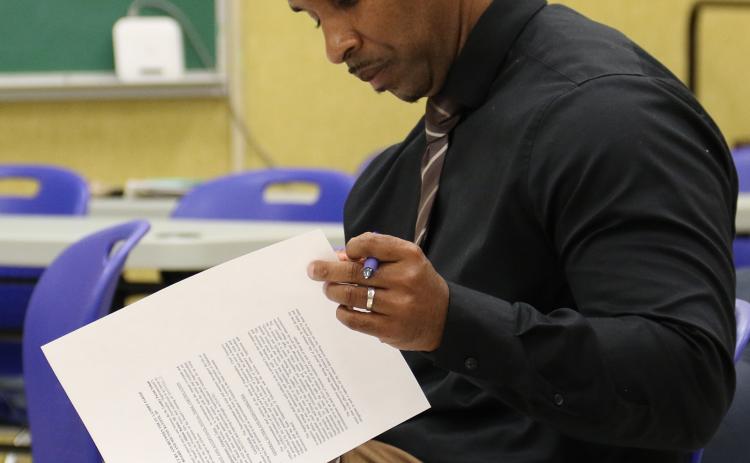 Milton Batiste, newly named St. Landry Parish school superintendent, goes over his contract at a special meeting on Tuesday. (Photo by Harlan Kirgan)