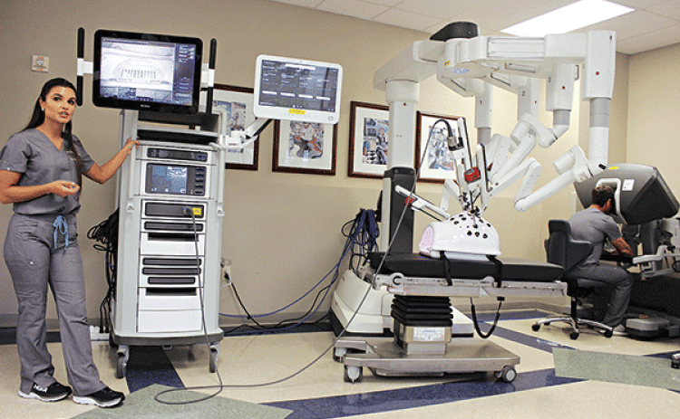 From left, are McKenzie O’Neal, and at far right, at the simulator surgeon console, Karl Lawrence, Clinical Territory Associate with Intuitive Surgical, presented and demonstrated Robotic surgical equipment to the Rotarians Wednesday.  (Photo by Myra Miller)