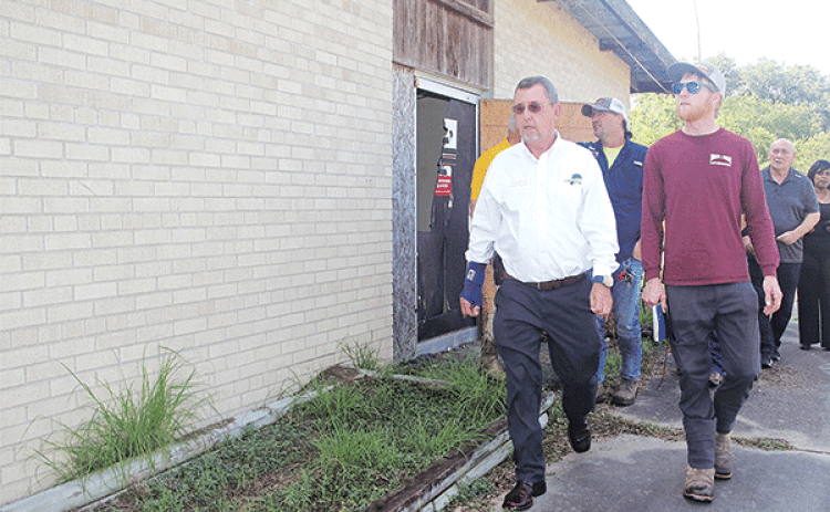 St. Landry Parish President Jessie Bellard, in the white shirt, leads a group on a walk around the vacant Moosa Memorial Hospital on Monday. He announced on Monday the building, vacant since 2006, will be demolished. At right in the red shirt is Phillip Cavins of Morgan and Morgan Land Preparation and Parish Council member Ernest Blanchard. (Photo by Harlan Kirgan)