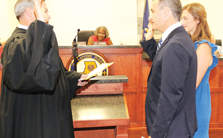 Dr. Zebediah Stearns recited an oath of office administered by District Judge Jason Meche at Wednesday’s St. Landry Parish Council meeting. With Stearns is wife, Christie. Seated, in the background is Nancy Carriere, Council vice chairwoman. (Photo by Harlan Kirgan)