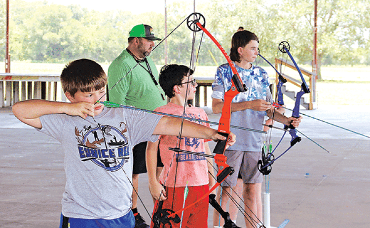 Above, from left, are Landry LeJeune, of Basile, Andre Guillory, of Eunice, and Max Daniel, of Baton Rouge, practice archery. Johnson is in the background.