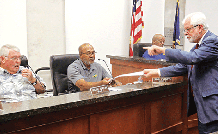 Gary McGoffin, right, an attorney representing the St. Landry Parish Council, hands out copies of a judgment to Parish Council members at a meeting Wednesday in Opelousas. Seated, from left, are Council members Wayne Ardoin, Jimmie Edwards and Jerry Red. The judgment is about a investigation by the Council into parish government employee terminations. (Photo by Harlan Kirgan)