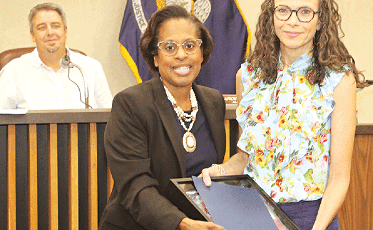 Eunice Alderwoman Germaine Simpson presents a flag and certificate to Paige Coutee in honor of Joseph “Joe” Coutee Jr. who operated Coutee’s Grocery. Looking on at left is Mayor Scott Fontenot. Turn to Page 10 for more photos from Tuesday’s city meeting. (Photo by Harlan Kirgan)