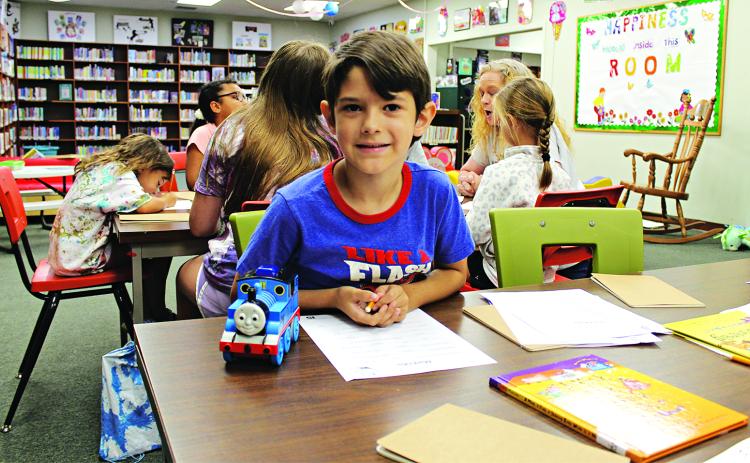 J.W. David, 7, begins to write his own story at the library Thursday morning during Imagination Camp.
