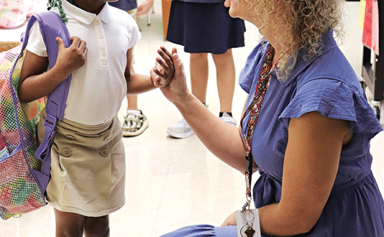 First-grade teacher Arien Harper greets one of her students, Valynn Edwards, on her first day of school.  Looking on are Jackson Guillory and Aria Faulkner, also in Harper’s class. (Photo by Amy Myers)