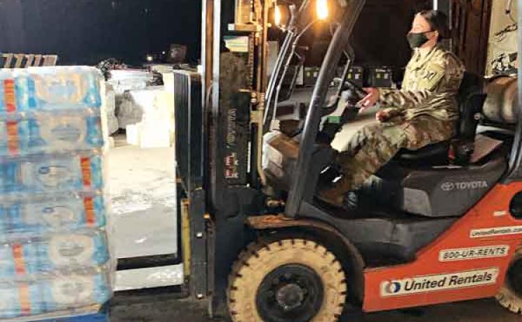 A Louisiana National Guardsman with the 769th Engineer Battalion loads a pallet of bottled water onto a high-water vehicle in order to be delivered to citizens in need during the winter storm at Camp Minden in Minden, on Feb. 19. The expansive infrastructure available on Camp Minden helps resolve large storage challenges presented during state emergencies. (U.S. Army National Guard courtesy photo from Louisiana National Guard)