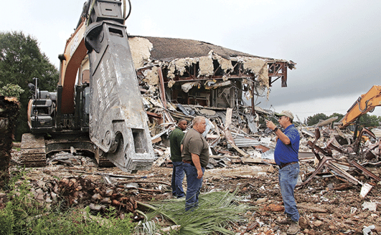 St. Landry Parish Government employees worked the weekend to demolish the second story of the old Moosa Memorial Hospital From left, are Eric Chisely, building maintenance supervisor; Jessie Bellard, parish president; and Todd Darbonne, fleet manager. They are by the shear tool used to cut through steel at the old hospital. (Photos by Harlan Kirgan)