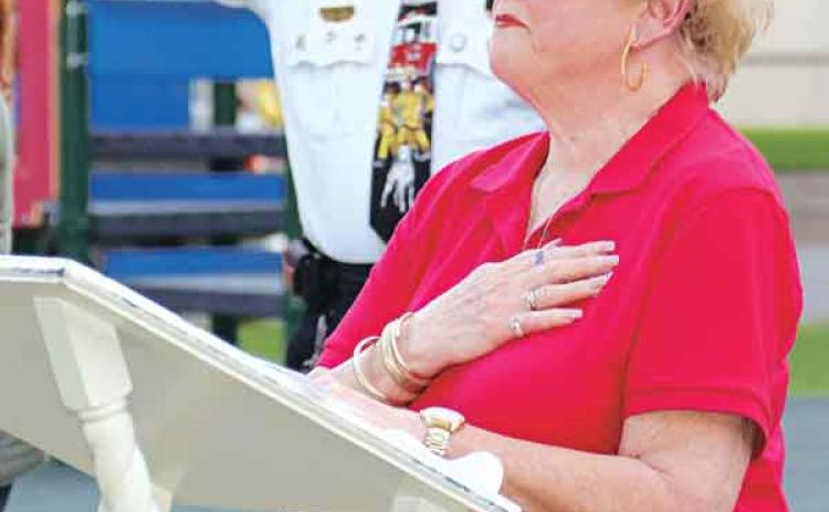 Evelyn Stringer, president of Woodmen Life Chapter 243, and Eunice Fire Chief Mike Arnold salute the flag at Saturday’s ceremony. (Photo by Harlan Kirgan)