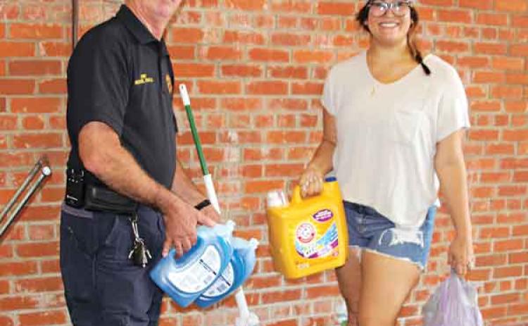 Lauren Leonards, of Mire, drops off supplies at the Eunice Fire Department central station for Hurricane Ida recovery efforts. Accepting bags of cleaning supplies and mops is Eunice Fire Chief Michael Arnold. (Photo by Myra Miller)