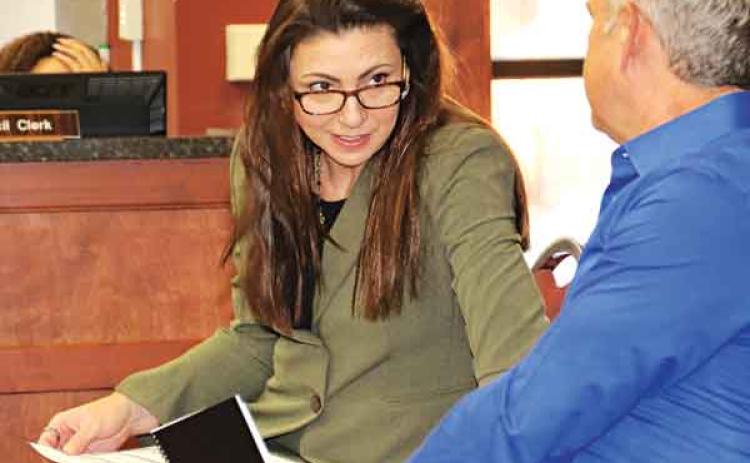 Sherri Zeringue McGovern, St. Landry Parish tax assesor, talks with Bill Rodier, parish economic development director, before Wednesday’s St. Landry Parish Council meeting in Opelousas. (Photo by Harlan Kirgan)