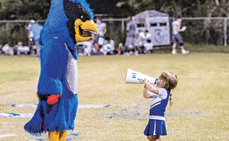 Karter Lejeune, 4,  uses a megaphone to chat with St. Edmund mascot Bluedreaux (Melody Fuselier) during last week’s game against Westminster Christian Academy. Karter’s parents are Dana and Jared Lejeune. Her brother, Jay, and sister, Caroline, are multi-sport athletes at St. Edmund. (Photo by Dwight Jodon)