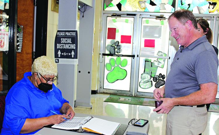 Debra Gallien, an election commissioner, views Dr. Jerome Fontenot’s driver’s license at a voting poll at Eunice High School Tuesday afternoon. (Photo by Myra Miller)