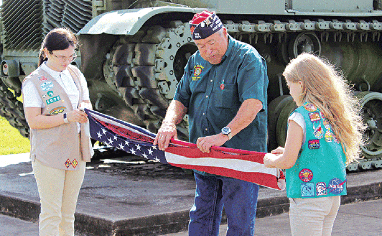 Girl Scout Troop 1016 members  Ava Ortego, left, and Kallie Bakka performed the flag-raising ceremony during the Veterans Day program held at the VFW 8971 Post Hall. Showing the two scouts the proper flag folding etiquette is Bob Witkovski, VFW Post 8971 quartermaster. Turn to Page 12 for additional Veterans Day photos. (Photo by Myra Miller)