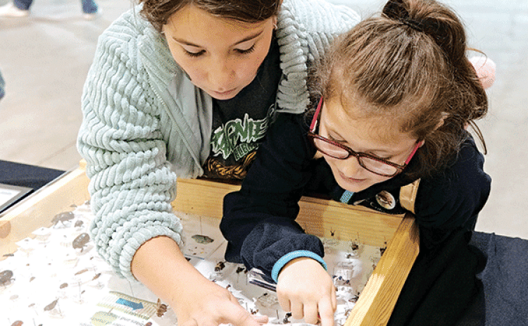 Two students from Chataignier Elementary School use a magnifying lens to examine insects at the LSU AgMagic Cenla event held at the State Evacuation Shelter Nov. 15 and 16. The students toured numerous stations highlighting agriculture, nutrition and health. (Photo by Craig Gautreaux/LSU AgCenter)