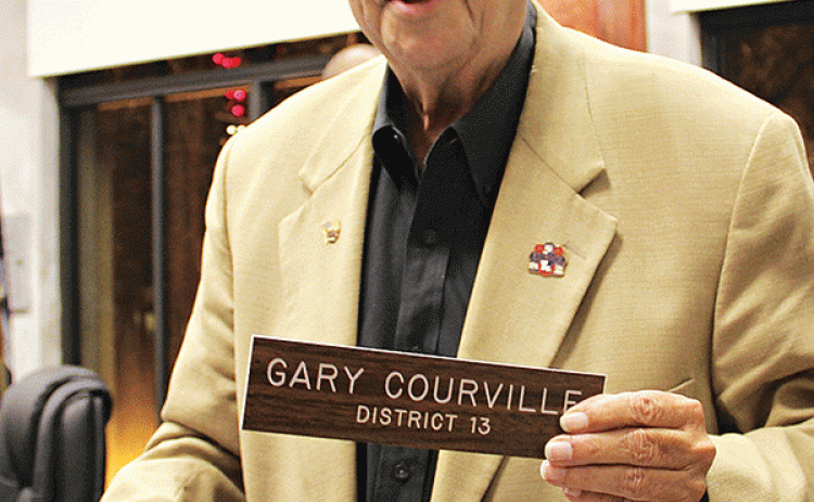 Gary Courville holds his nameplate at the St. Landry Parish Council meeting room during his final meeting. Courville, who held office for 23 years, died on Nov. 30. (File photo)