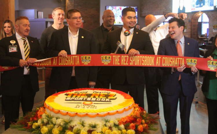 Flanked by members of the Coushatta Tribal Council Crystal Williams, Kristian Poncho, Loretta Williams, and Kevin Sickey, Chairman Jonathan Cernek (center) cuts the ribbon at the grand opening of The Rez Sportsbook in Kinder. From left, in the back, are former NFL players Owen Daniels, Rickey Jackson and Drew Pearson. (Ville Platte Gazette photo by Tony Marks)