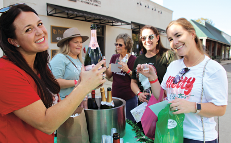 Greta Fontenot was in charge at one  of many sipping stations along South and North 2nd Street in Eunice during a Sip and Stroll event held Saturday. Fontenot pours a sample of one of the wines to Anne Marie Habetz. 