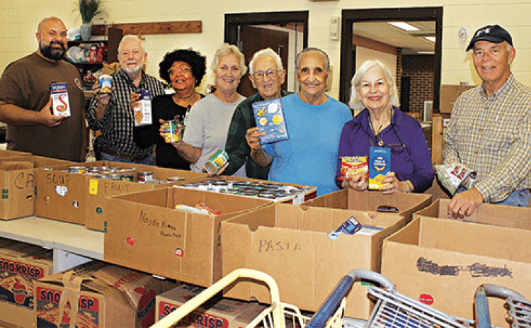The Eunice Food Bank annual Food Drive was held Tuesday. Many volunteers were on hand ‘giving a hand.’ The early morning volunteers at the food bank included, the Rev. Heath McWilliams, left, David Guillory, Mary Ann Guillory, director; Jean Vige, Harry Reed, Tina Thomas, Darilyn Ardoin and Ron Driggs. (Photos by Myra Miller)