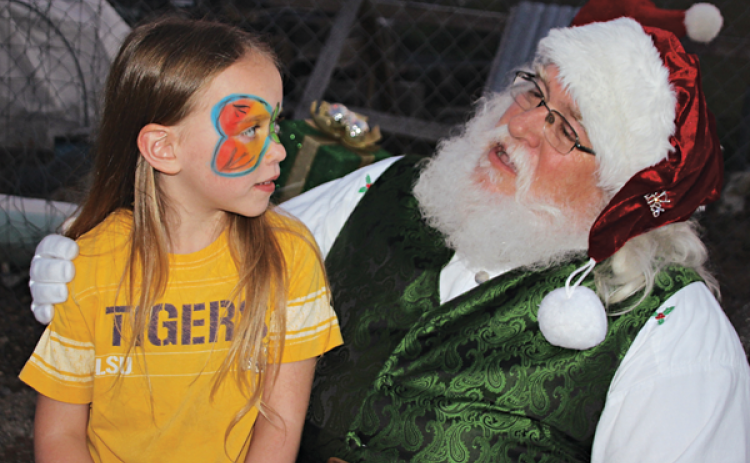 Ellie Lyons, 7, and Santa have a nice chat at the Eunice Community Garden Christmas Festival Thursday evening. The Eunice Community Garden had its first ever Christmas Festival Thursday evening. There were over 15 booths at the Eunice Community Garden.  Many Eunice businesses, organizations, civic clubs, churches, LSUE and individuals were part of the event. Some booths gave free gift items and tokens, arts and crafts, while other booths held games and activities for kids. Randy Miller is the director of th