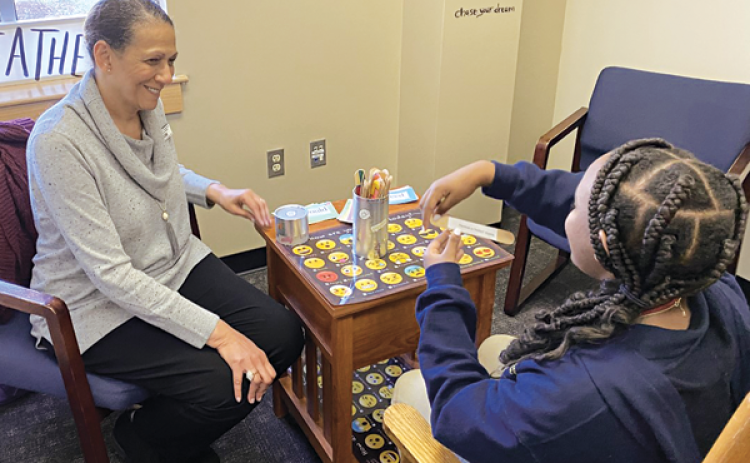 Dr. Susan Thornton, a care specialist at a middle school has one of her students hold a pop stick with a conversation starter line glued to it, an activity to help teens open up. (Photo courtesy of Dr. Susan Thornton)