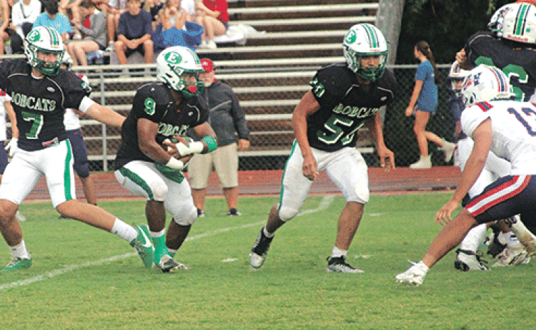 The Eunice High Bobcats started off slow, but made adjustments and defeated the North Vermilion Patriots 14-6 in a jamboree contest on Aug. 29 in Rayne. From left, Montana Brown, quarterback,completes a handoff to running back Bryan Allen as guard Christopher Malbrough leads for a block. (Photo by Rhett Manuel)
