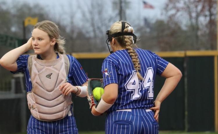 St. Edmund catcher Jenna Smith meets with Lady Jay pitcher Nicole Evans during a timeout against Menard.