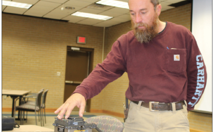 Kenny Miller is next to a fusing machine. A fusing machine he has is for fiber optic. Miller said, “It goes through and takes your fiber optic glass, fuses and welds it together and makes a connection, and this can be used for video, and internet.” Miller was the Rotary Club’s guest speaker Wednesday. He was the guest of Alex Morris. (Photo by Myra Miller)