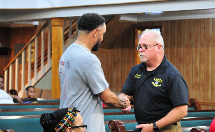 Chief Kyle LeBouef and Paul DeRousselle shaking hands after receiving the award