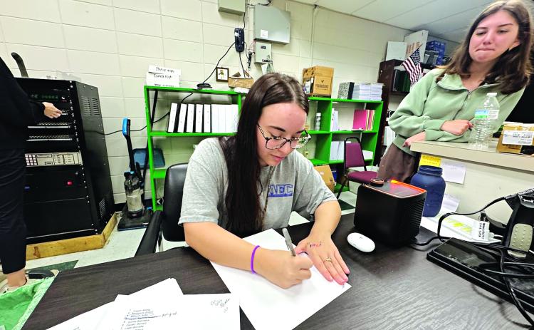 Lainey Fruge, 17, of Eunice High School, writes her name in cursive, while classmate Kelsie  Gaspard, 18, watches. Both students said they only know how to write their names in cursive. (Photo by Rebecca Chaisson)