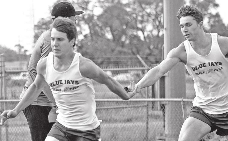St. Edmund’s Luke Trahan takes the baton from Easten Coleman. (Photo by Tom Dodge)
