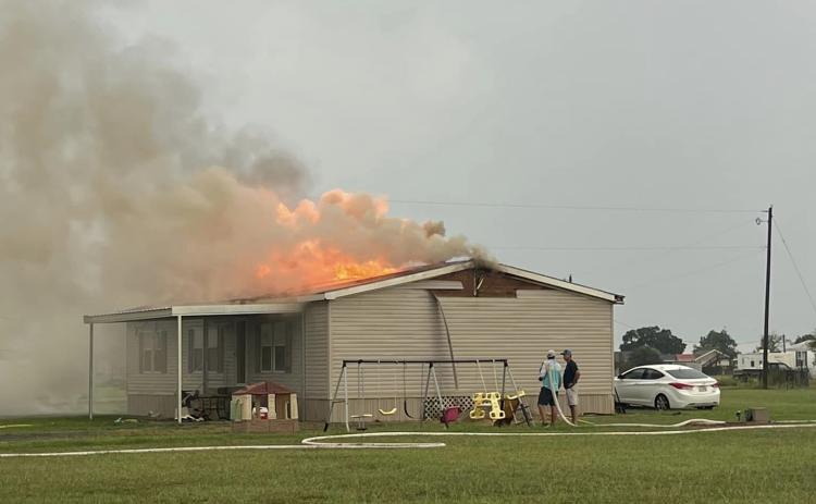 The home of Neal Leger and Janice Arnold on Pelican Loop near Basile was a complete loss as the result of a fire caused by a lightning strike. The fire is shown above in the roof before it overtook the entire home. (Submitted photo)