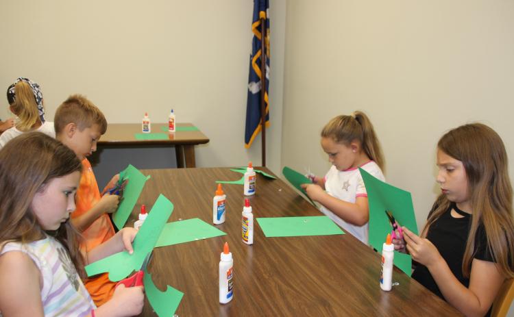 Older children enjoy crafting a gecko at the library.