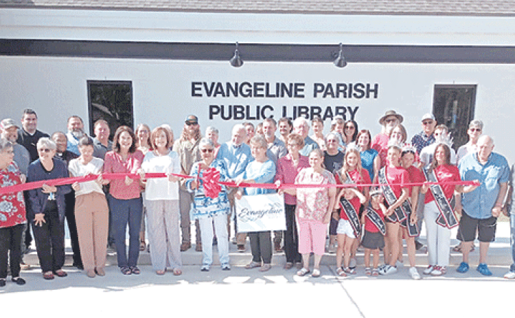 Local and parish library board members and employees, pastors, community leaders, library patrons, and Miss Basile royalty along with contractors who built the new Basile library branch building are gathered around Faye Langley, local representative on the Evangeline Library Board of Control, as she cuts the ceremonial ribbon at the library’s grand opening.