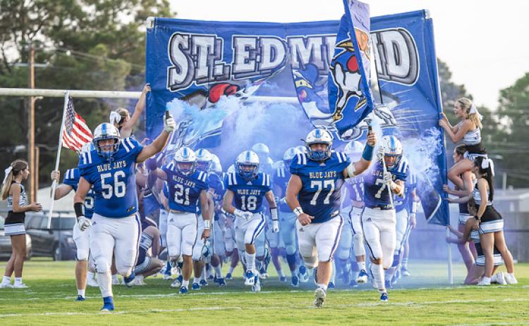 St. Edmund runs through its banner before the Oakdale game.