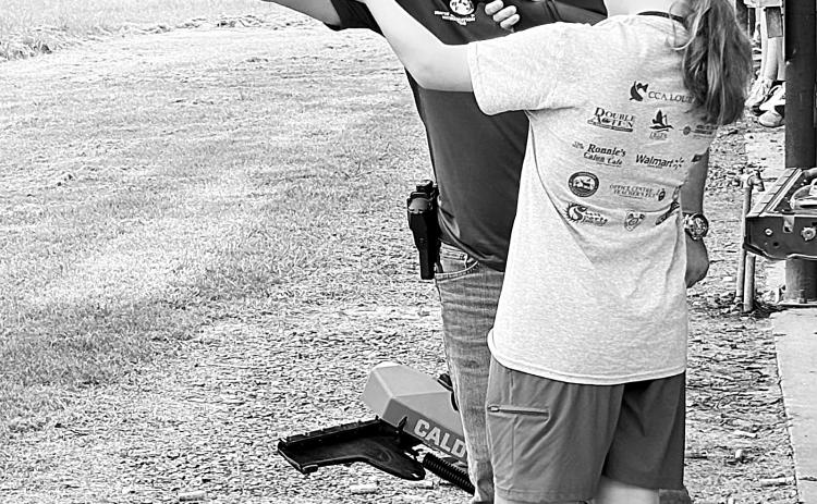 Instructor teaching girl how to properly operate a shotgun